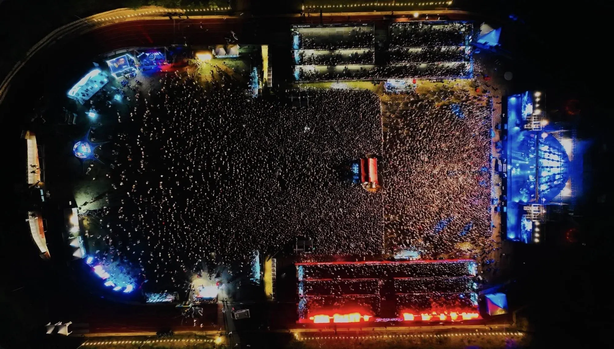 Aerial view of the illuminated stage and audience at an outdoor concert at night