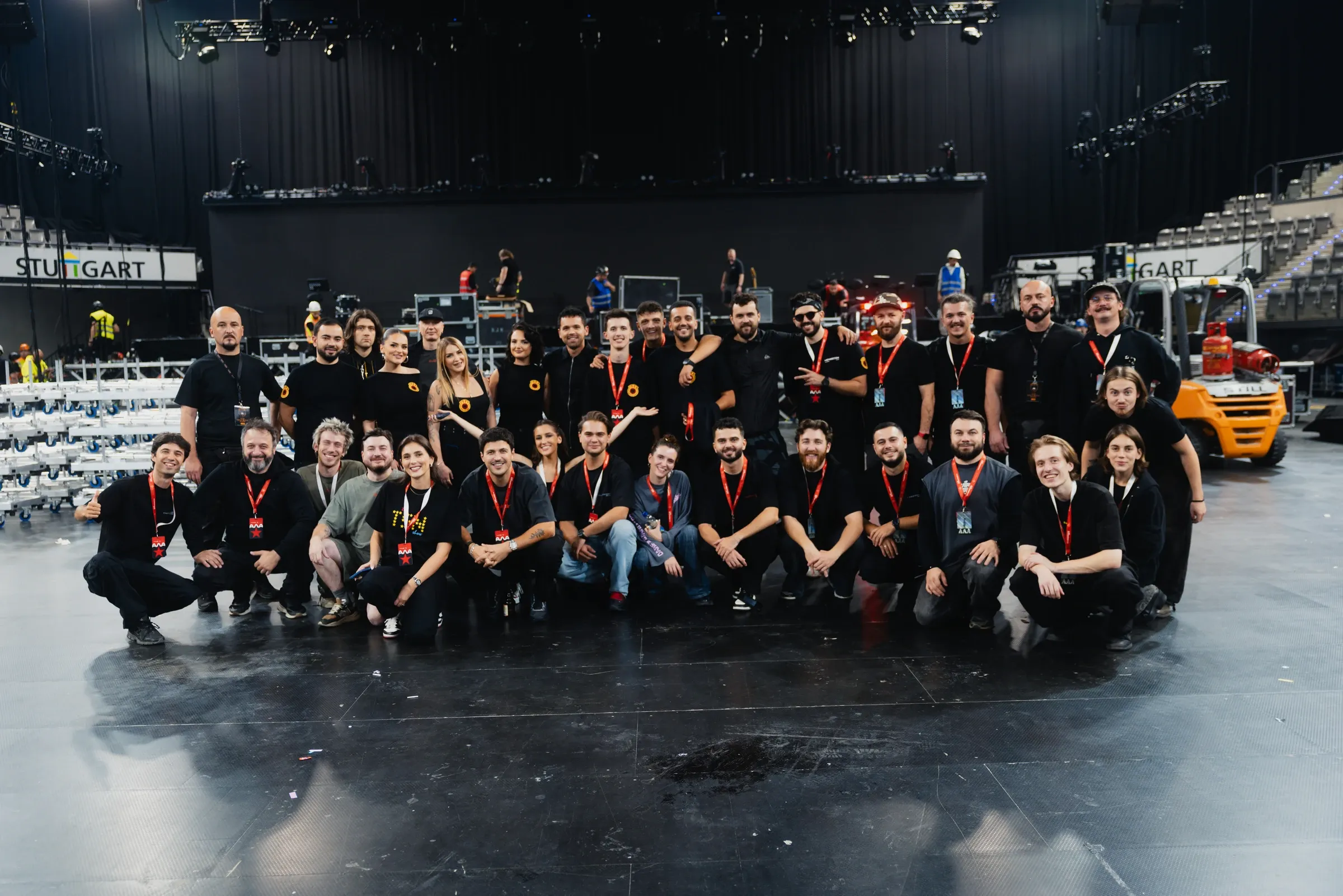 Yll Limani tour team posing together in front of the stage at the Stuttgart arena