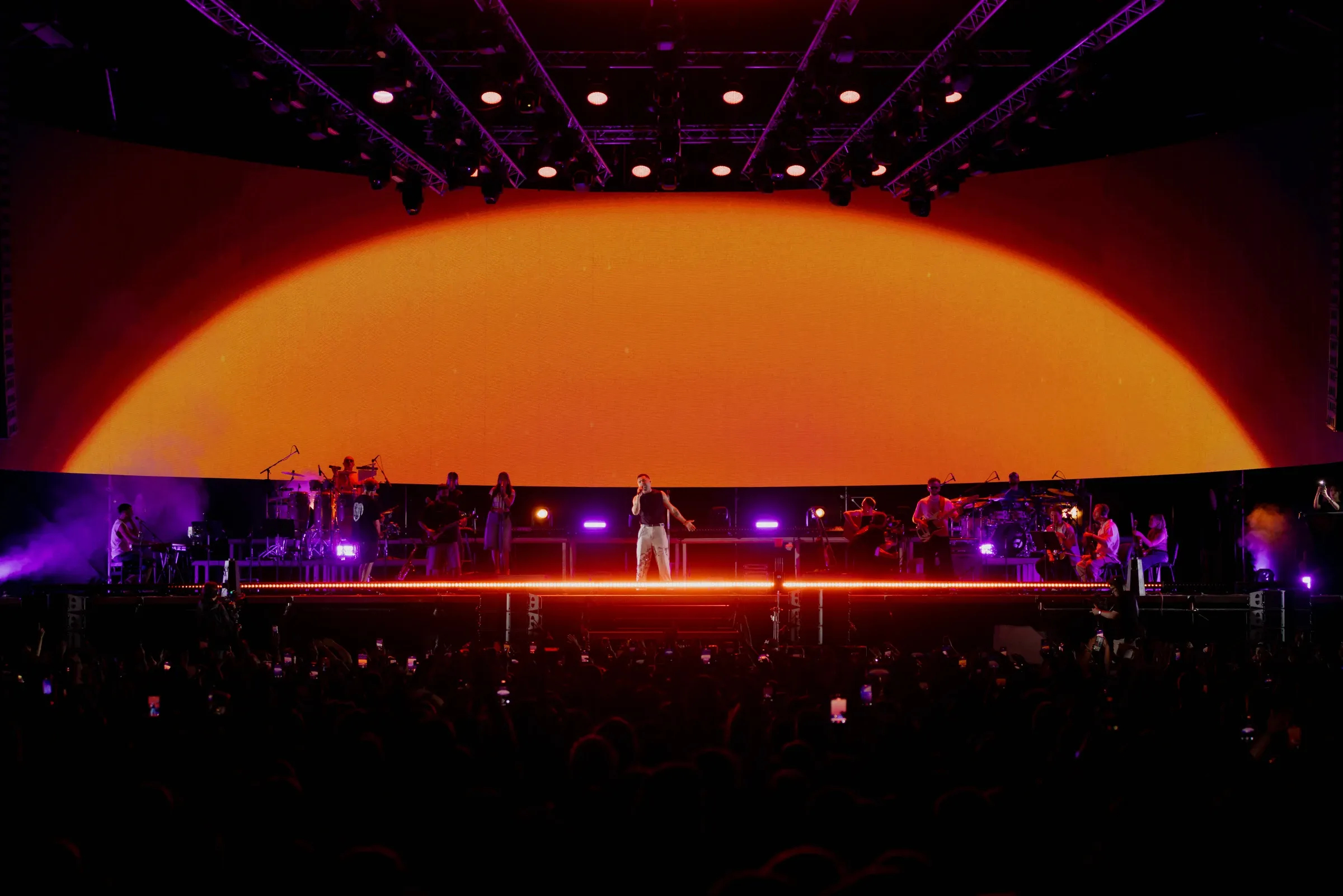 Orange sunrise visuals filling the curved stage screen