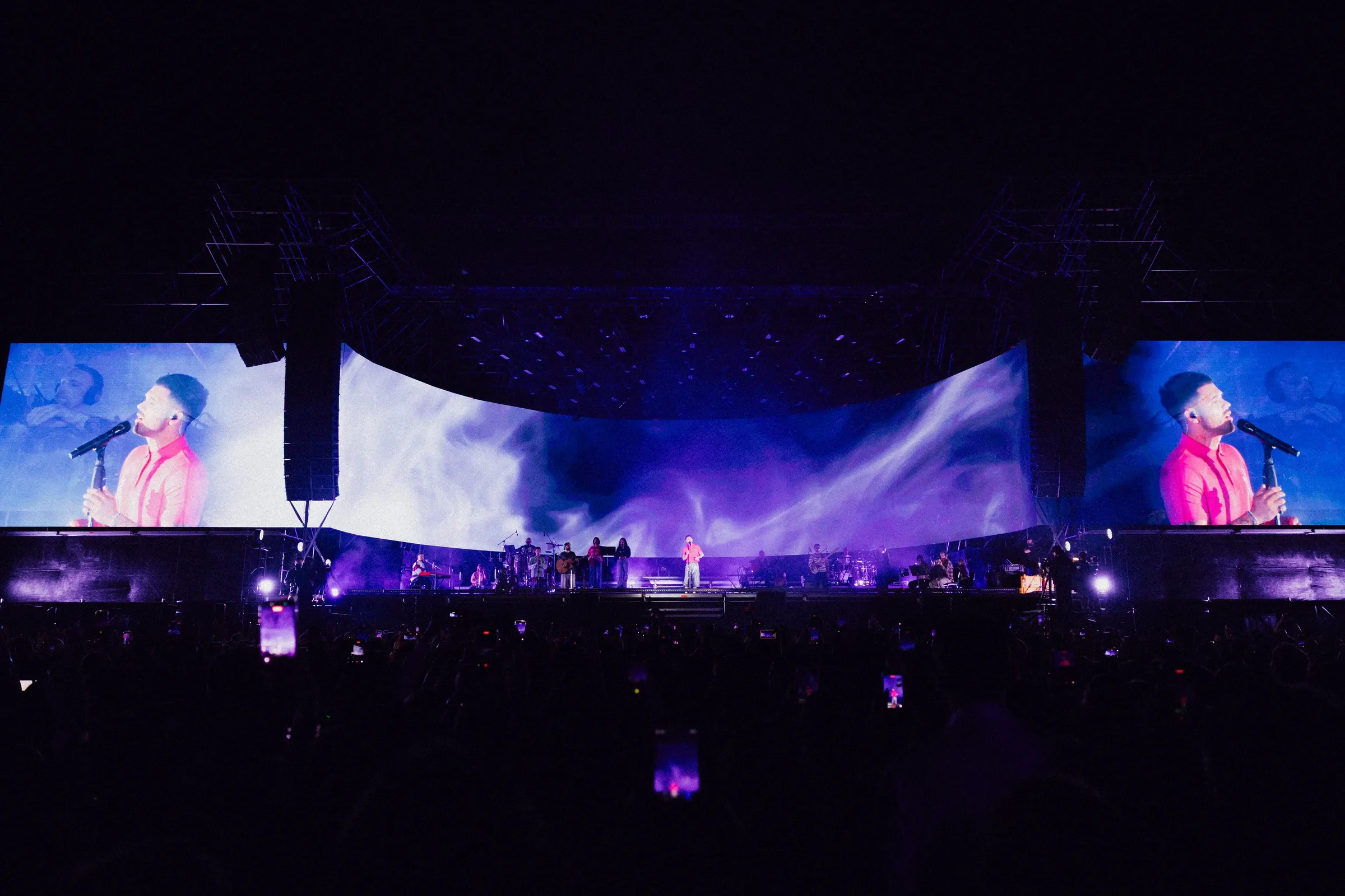 Outdoor stage with blue and white visuals across the curved screen