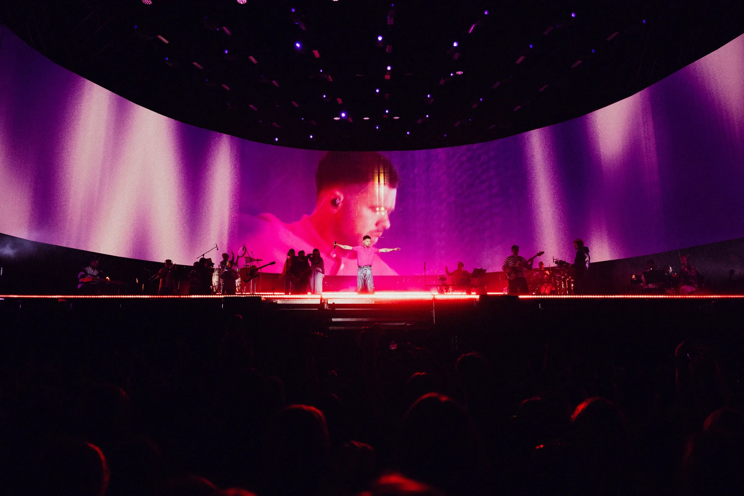 Purple screen visuals framing the singer at centre stage