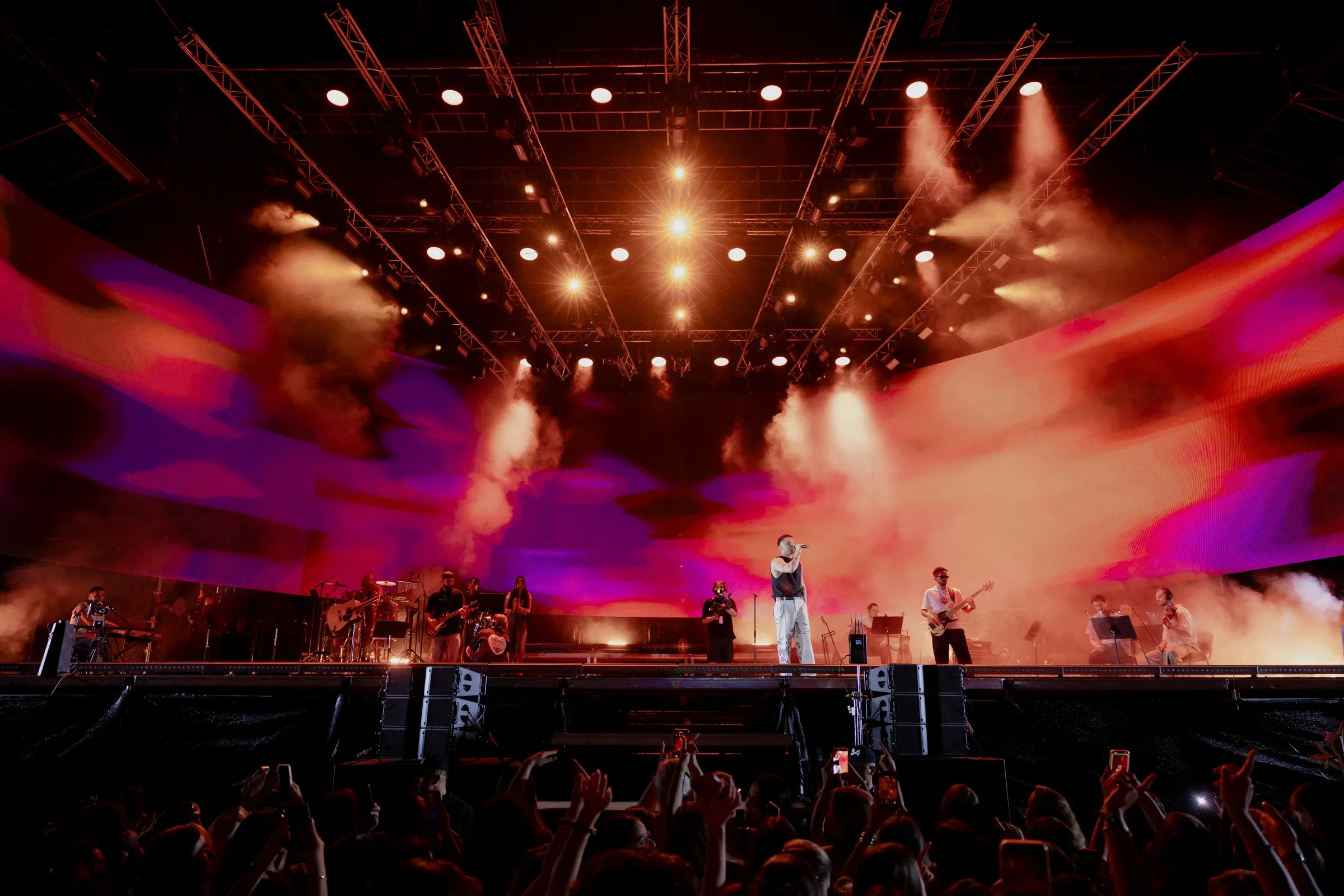 Warm stage lights and smoke above the performers and audience