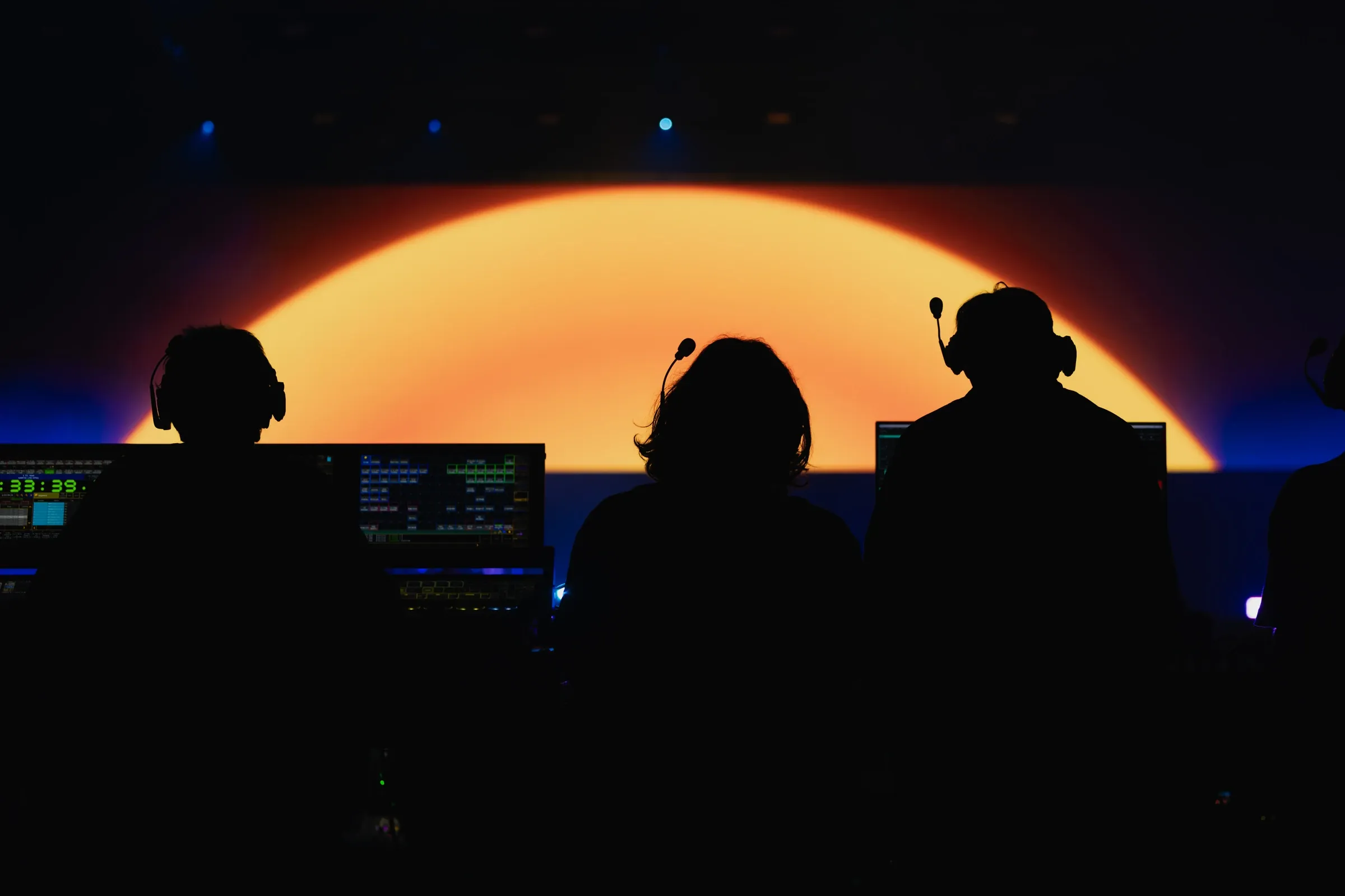 Show operators at their control consoles with the illuminated stage in the background