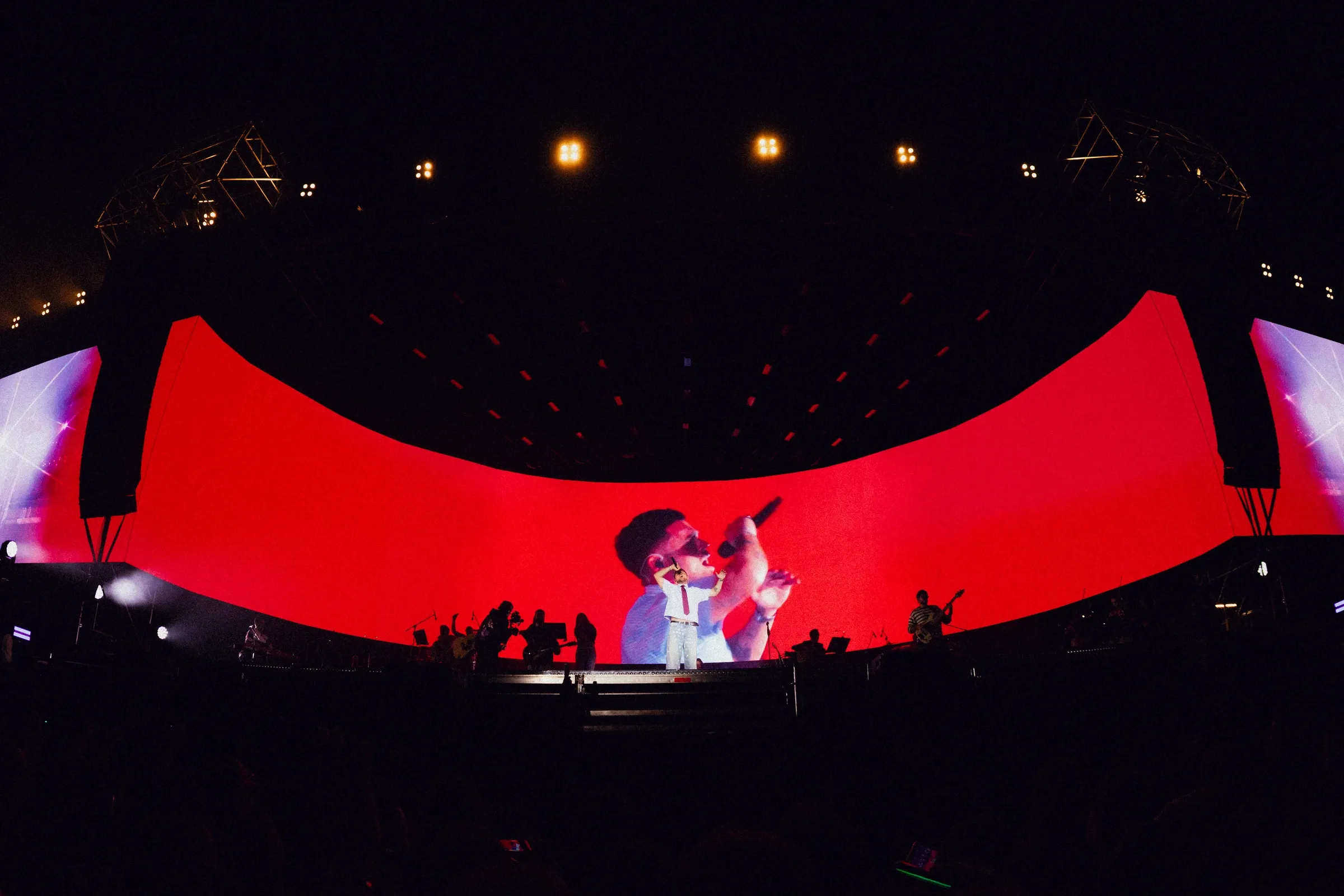 Yll Limani performing in front of the curved red LED screen with a live close-up of the singer
